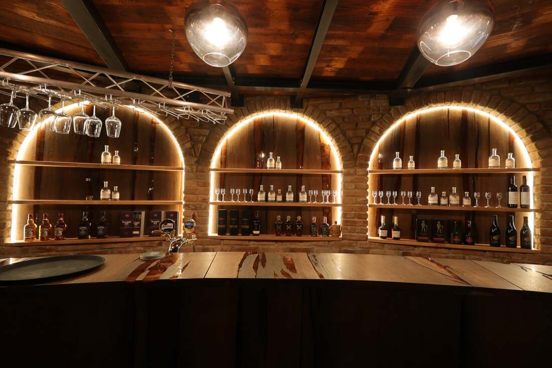Bar s tromi podsvietenými oblúkovými regálmi plnými fliaš