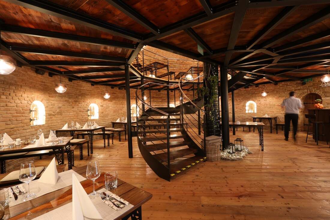 Prestreté stoly v sále Galérie, na pozadí čašník obsluhujúci hostí